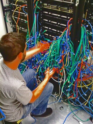 Louie Christie in a computer server room, plugging in network cables.